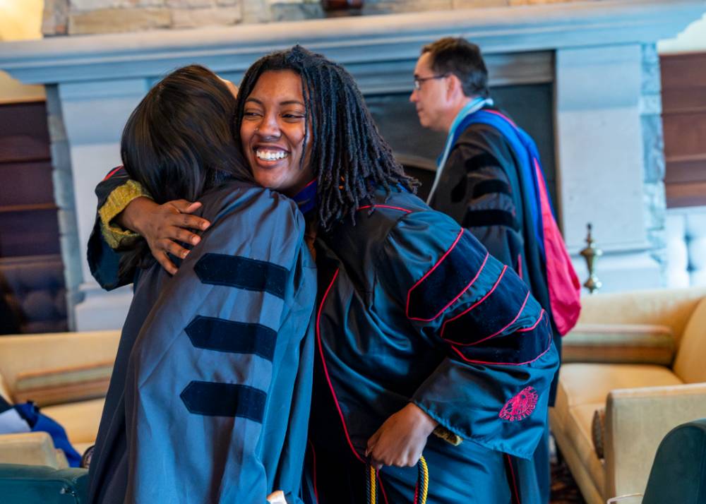 Faculty hugging one another
